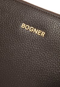 Portafoglio in pelle marrone con texture, dotato di un logo dorato "BOGNER", chiusura con zip e una leggera texture sulla superficie.