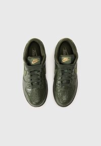 Nike sportbačiai tamsiai žali, su tekstūriniu, blizgiu paviršiumi, primenančiu krokodilo odą. Yra raišteliais verčiama dizaino ir auksiniai logotipo akcentai.