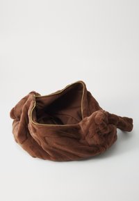Borsa in peluche marrone con una texture morbida, forma arrotondata e zip dorata. Interno foderato con un tessuto marrone uniforme.