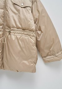 Chaqueta de plumas beige con cierre frontal, cinturilla elástica y bolsillo en el pecho con botón a presión. Tejido liso y brillante con un corte relajado.