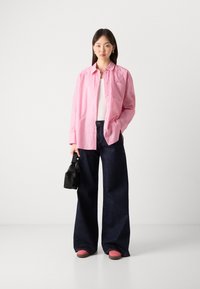 Striped pink button-up shirt, white tank top, dark wide-leg jeans, pink sneakers, and a small black bag. Simple and modern design.