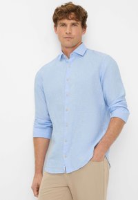Lichtblauwe button-up shirt van linnen, met een spreidkragen, opgerolde mouwen en een subtiele textuur. Bruine knopen vormen de details aan de voorkant.