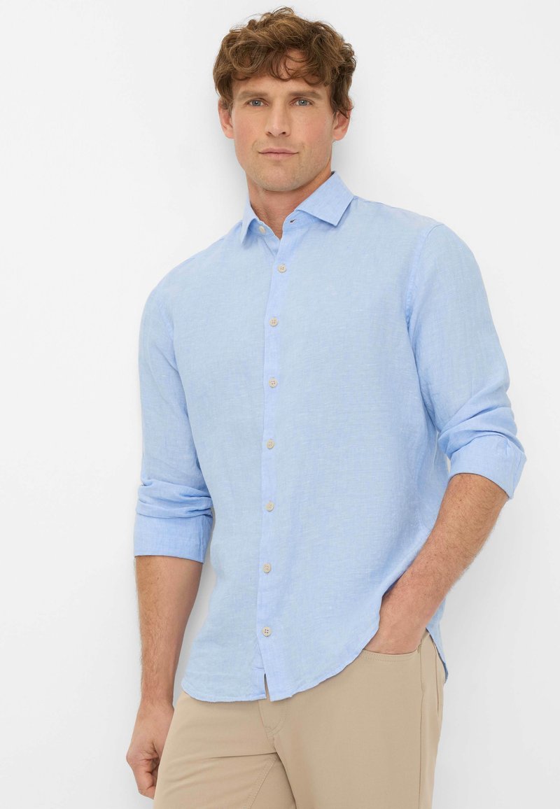 Camicia button-down azzurro chiaro in lino, con colletto spread, maniche arrotolate e una trama sottile. Bottoni marroni decorano la parte anteriore.