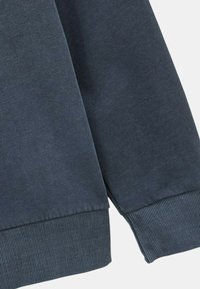 Sweatshirt marine dans le coin mettant en avant un tissu texturé, des poignets côtelés et un ourlet droit. Design minimaliste avec une finition lisse.