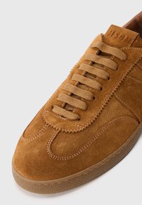 Baskets en daim marron à surface texturée, bout rond et lacets plats. Présente des accents cousus et une semelle en caoutchouc avec un bord légèrement transparent.