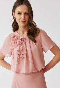 Rosa Chiffon-Bluse mit kurzen Ärmeln, die auf der Vorderseite mit geschichteten, blütenblattähnlichen Verzierungen versehen ist und einen lässigen Schnitt hat.