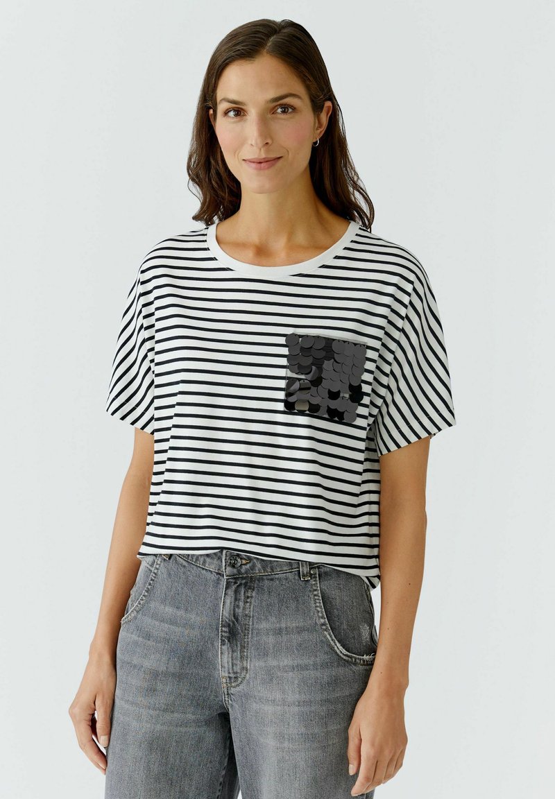 Schwarz-weiß gestreifes T-Shirt mit kurzen Ärmeln, rundem Halsausschnitt und einer schwarzen Pailletten-Patch-Tasche auf der linken Seite.