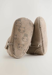 Des pantoufles douces de couleur taupe en daim avec des motifs de visages d'animaux. Forme arrondie avec des accents brodés et des semelles flexibles.