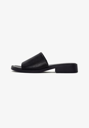 Black slide sandal with wide leather strap, low block heel, and flat sole, shown in side profile on white background.