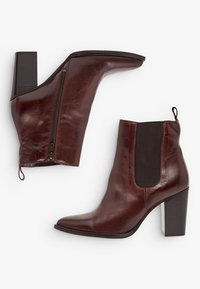 Bottines en cuir marron à talon bloc haut, avec fermeture éclair sur le côté et panneau élastique, présentant une texture lisse et une forme de orteil angulaire.