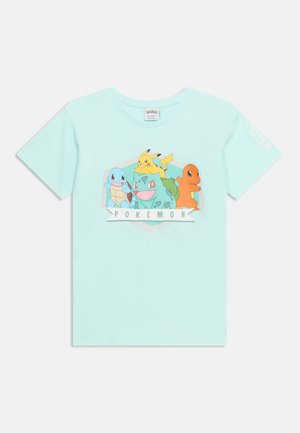 Világoskék póló, amelyen Squirtle, Bulbasaur, Pikachu és Charmander látható, a "Pokémon" felirat felett, elöl középen.