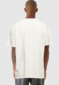 Weißes Baumwoll-T-Shirt mit kurzen Ärmeln, rundem Ausschnitt und lässiger Passform. Die Rückseite hat eine glatte Textur und weist keine sichtbaren Logos oder Designs auf.