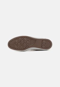 Talpa de sneaker din cauciuc maro cu modele în diamante și orizontale, având o margine albă. Textul logo-ului vizibil pe talpă, design clar pentru aderență.