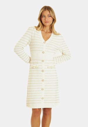 Robe cardigan blanche avec des rayures dorées verticales, col en V, boutons sur le devant, taille côtelée et poches décoratives. Texture douce.
