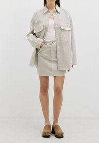 Gestreepte shirt in lichte tinten met twee voorzakken, gecombineerd met een bijpassende minirok en bruine klompen. Soepele stof, casual pasvorm.