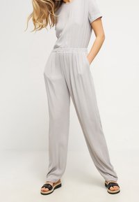 Szary, krótki kombinezon z elastycznym pasem i bocznymi kieszeniami. Połączony z czarnymi sandałami z szerokim paskiem i platformą.