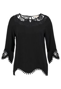 Blouse noire avec empiècement en dentelle et manches 3/4, ornée d'un bord en dentelle festonnée et de détails à pompons sur l'ourlet et les manches.