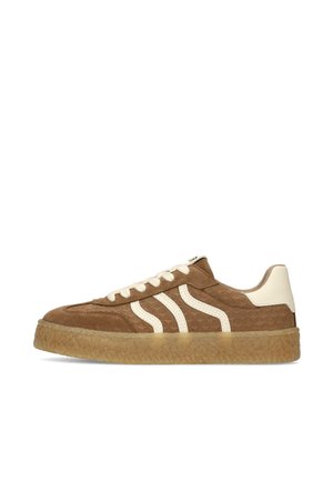 Brown suede sneaker with cream leather accents, white laces, textured gum sole, and two wavy cream stripes on side.