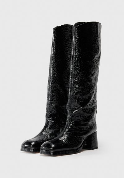 Botas negras hasta la rodilla hechas de cuero texturizado brillante, con punta cuadrada y un tacón bloque grueso. Acabado suave con costuras mínimas.