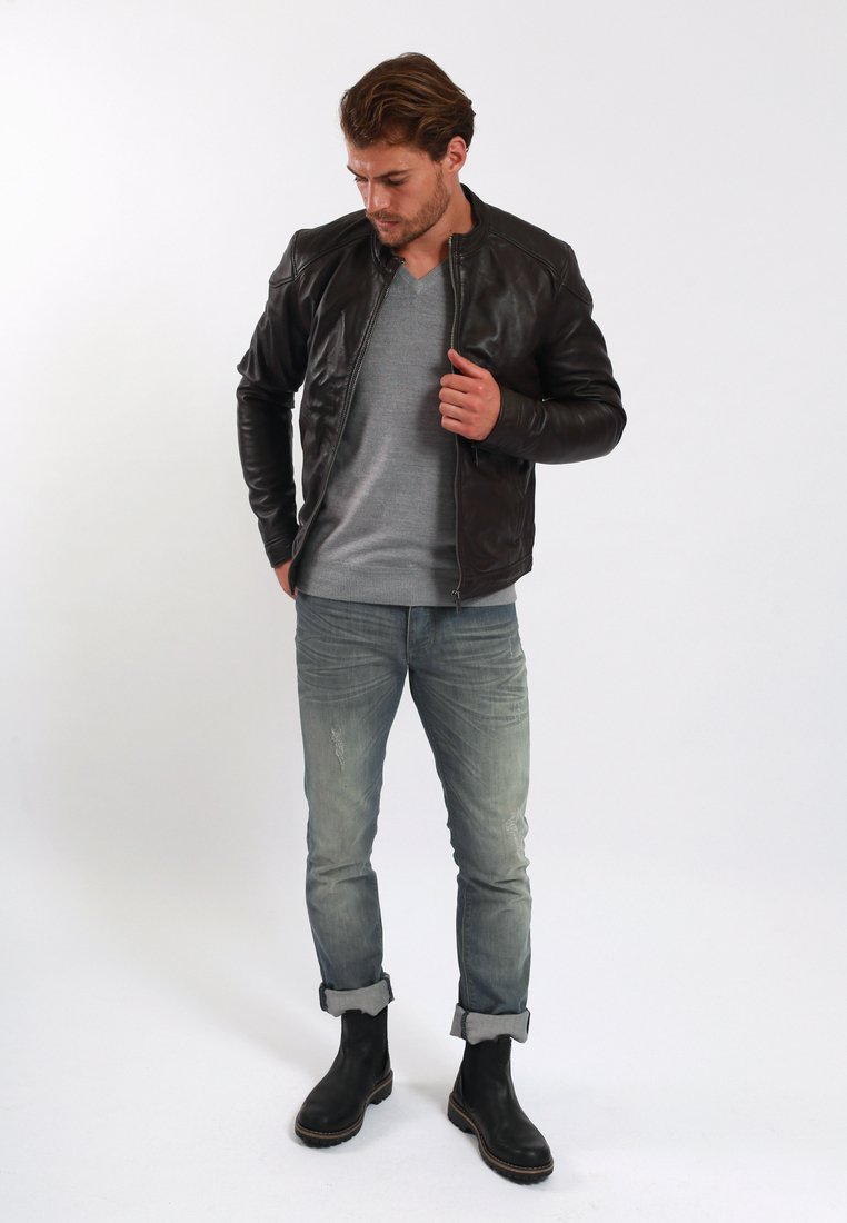 Chaqueta bomber de cuero marrón, suéter gris, jeans deslavados y botas negras de tobillo. Textura suave con detalles acanalados y un ajuste relajado.