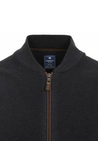 Dunkelblaue Zip-Jacke mit strukturiertem Strickmuster, ausgestattet mit einem Reißverschluss aus braunem Leder und einem gerippten Kragen. Das Etikett trägt die Aufschrift "REDMOND Casual."