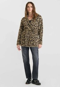 Cardigan de estampado de leopardo en tonos marrones y negros, con diseño envolvente, cinturón y mangas largas, combinado con jeans oscuros y zapatos negros.