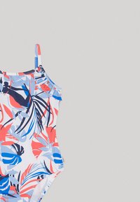 Meisjesbadpak met een kleurrijk koraal-, blauw- en marineblauw tropisch bladerenprint en een ruffle-detail op één schouderbandje op een grijze achtergrond.
