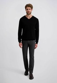 Zwarte V-hals trui, grijze broek en donkere schoenen. Glad materiaal, getailleerd ontwerp, lange mouwen en rechte pijpen met een subtiele structuur.