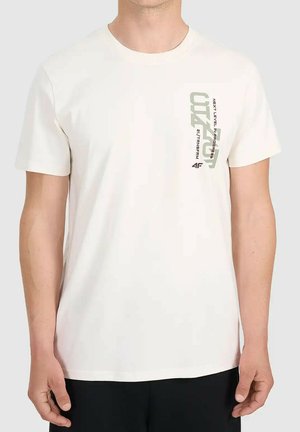 Mężczyzna w gładkiej białej koszulce z krótkim rękawem z pionowym napisem "NEXT LEVEL IN PROGRESS" oraz "CUT4" na piersi.