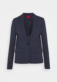 Blazer bleu marine à un bouton avec revers crantés et poches à rabat, avec une étiquette intérieure rouge et une doublure lisse.