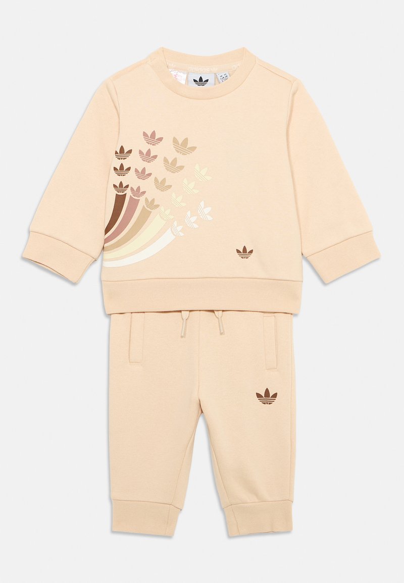 Ensemble de survêtement bicolore beige clair fabriqué en tissu doux. Comprend un sweat-shirt à encolure ras du cou avec des motifs de feuilles multicolores et un pantalon de jogging assorti.