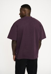 Oversized lilla t-shirt lavet af bomuld, med korte ærmer og rund hals. Glat tekstur med en lille detalje ved sømmen.