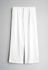 Witte wijde broek met elastische tailleband en voorste trekkoord, getoond tegen een lichtgrijze achtergrond.