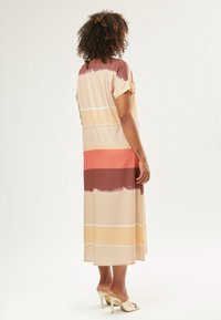 Vestido midi fluido en tonos en capas de marrón claro, rosa y marrón, con mangas cortas y un corte relajado. Tela suave con patrones horizontales.