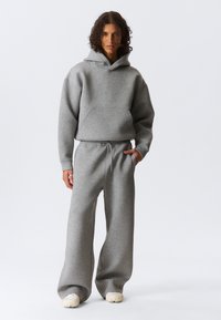 Gray hooded sweatshirt and matching sweatpants made of soft fabric, featuring a front pocket and drawstring waist, with relaxed-fit legs.