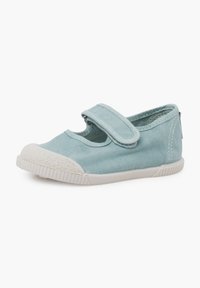 Zapato de lona azul claro con punta redonda, suela de goma blanca y correa de Velcro en la parte superior; cuenta con detalles de costura en los laterales.