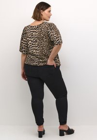 Top s krátkým rukávem v leopardím vzoru, lehký materiál, volný střih, doplněn černými skinny džíny a černými sandály na blokovém podpatku.