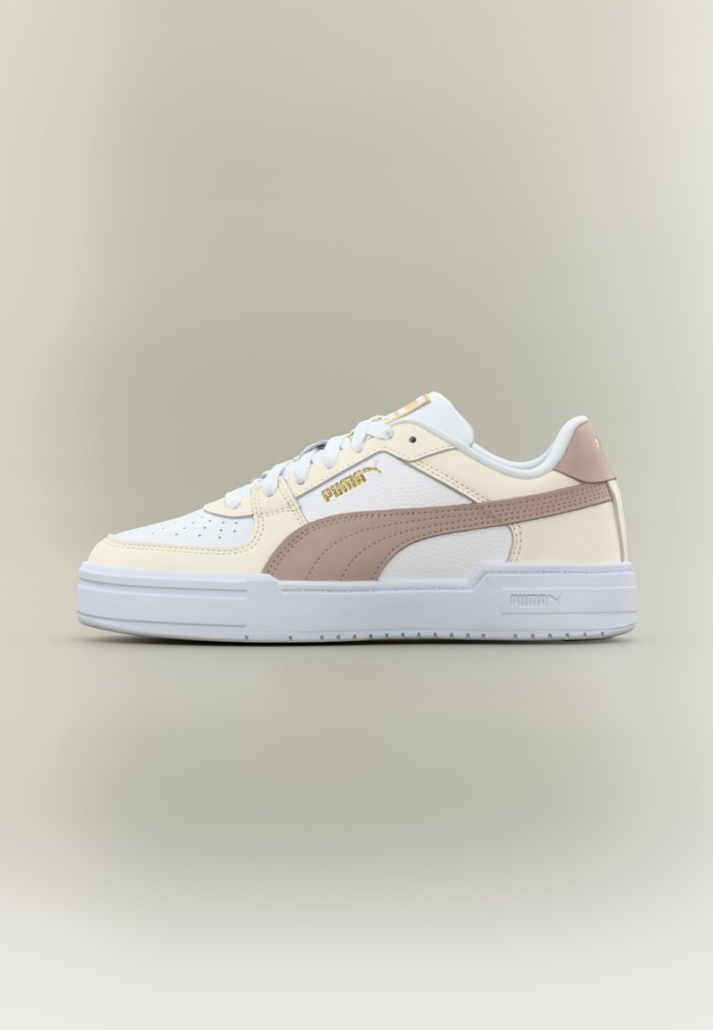 Baskets Puma blanches et beiges avec une bande marron clair, logo Puma doré et semelle blanche, vues de côté sur un fond neutre.
