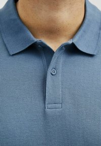 Polo shirt in zachte, textuurstof katoen, met een lichtblauwe kleur, een klassieke kraag en een dubbele knoopsluiting. Geweven patroon details zichtbaar.