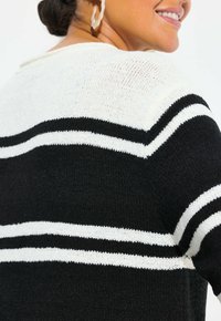 Schwarz-weißer gestreifter Pullover mit gestrickter Textur, rundem Ausschnitt und kurzen Ärmeln. Streifen in unterschiedlichen Breiten sorgen für Kontrast.