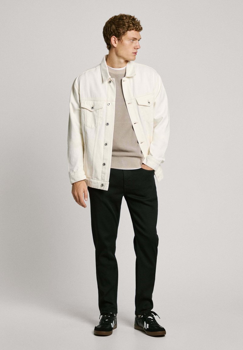 Weiße Jeansjacke, grauer Pullover, schwarze Hose, schwarze Sneakers. Mit Knöpfen, zwei Brusttaschen und kontrastierenden Texturen. Schlichtes, lässiges Design.