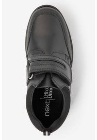 Chaussure en cuir noir avec une sangle Velcro, semelle intérieure rembourrée, bout arrondi et accents texturés. Comprend un logo à l'intérieur et un détail rayé au niveau du talon.