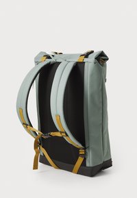 Zaino roll-top di colore verde tenue con spalline gialle, una base robusta e uno schienale in rete traspirante, dotato di spalline regolabili per il massimo comfort.