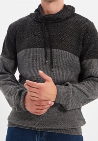 Gebreide pullover in zwart en grijs, met een hoge kraag, koordje en getextureerde patronen. Comfortabele pasvorm met geribde cuffs en zoom.