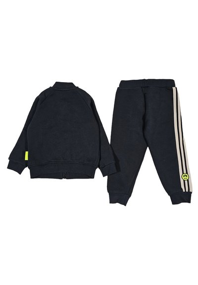 Felpa blu navy con dettagli gialli e pantaloni jogger abbinati caratterizzati da strisce beige chiaro e un logo sorriso verde sulla gamba.