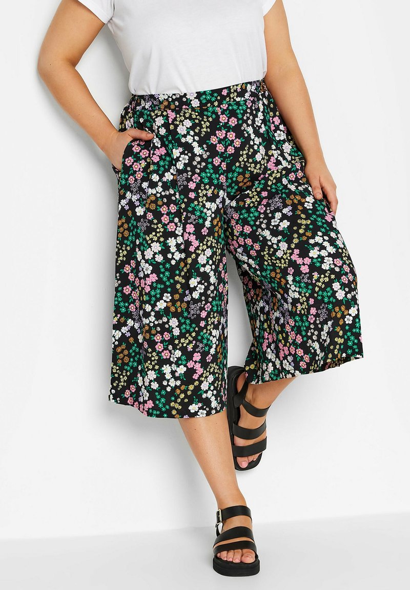 Svarta blommiga culottes med färgglada blommor och gröna accenter. Har ett elastiskt midjeband och sidofickor. Kombineras med svarta sandaletter.