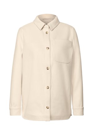 Veste chemise beige à boutons en tissu doux, avec une poche poitrine unique, un ourlet arrondi et des boutons dorés.