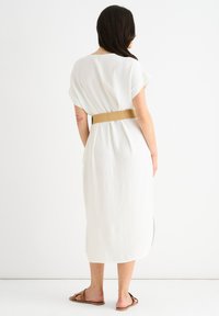 Abito bianco, al ginocchio, con una vestibilità comoda, maniche corte e una vita accentuata da una cintura intrecciata beige. Texture sottile, senza motivi.