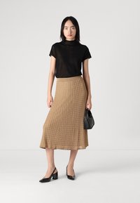 Musta lyhythihainen paita, beige ribattu midihame, mustat avokkaat ja pieni musta käsilaukku. Sileät kankaat ja jämäkkä muotoilu.