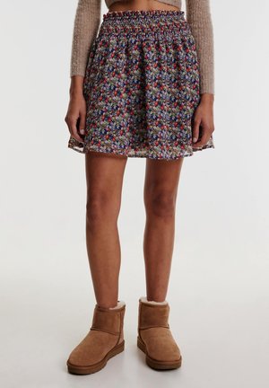 Rock mit Blumenmuster und schmalem Bund, in mehreren Farben auf dunklem Hintergrund. Kombiniert mit braunen Ankle Boots mit Fellfutter.